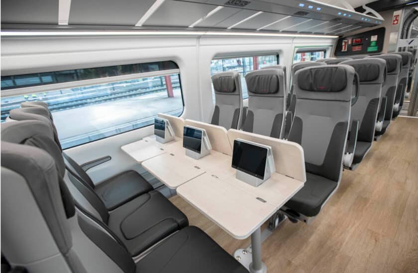 Filas de 3 asientos y pantallas sobre la mesa en el interior de un Talgo Avril. © RENFE.