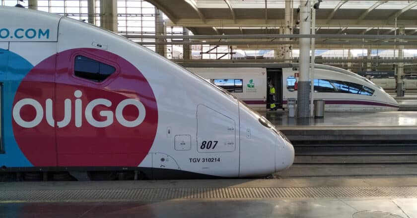 Un tren de la serie 108 de Ouigo con un 103 de Renfe en el fondo en la estación de Madrid Puerta de Atocha. © MIGUEL BUSTOS.
